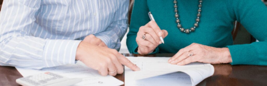 two people signing documents at a table