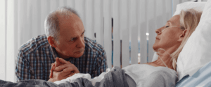 A woman laying in a hospital bed while her husband holds her hand