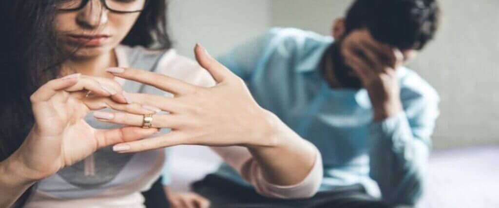 woman removing her wedding ring from her finger while her husband is upset